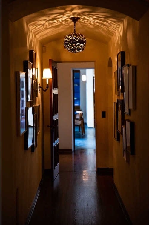 这是一条米色的走廊，铺着硬木地板，墙上挂着许多镶框艺术品。图片来自Toptenrealestatedeals.com。