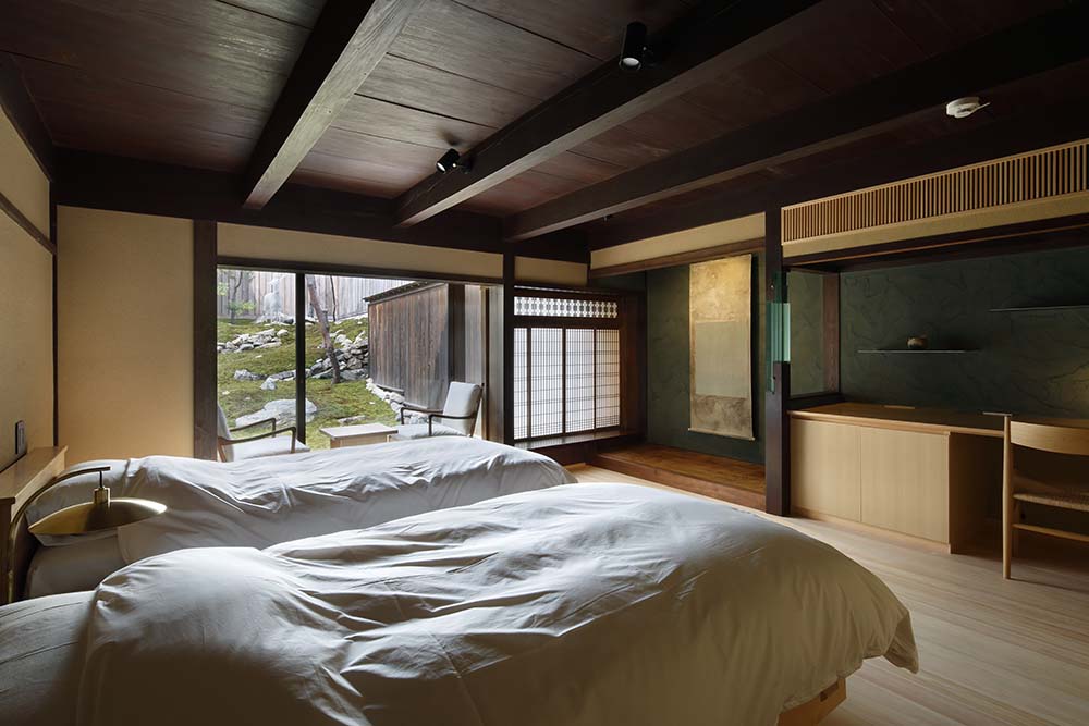 这是近距离观察其中一间卧室，它有两张白色的床，辅以浅色硬木地板和深色木质天花板。