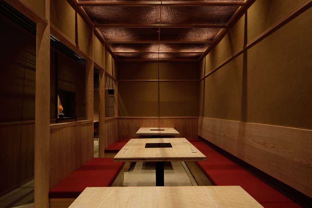 餐厅的桌子与墙壁上嵌壁式长椅的鲜红色靠垫形成对比。