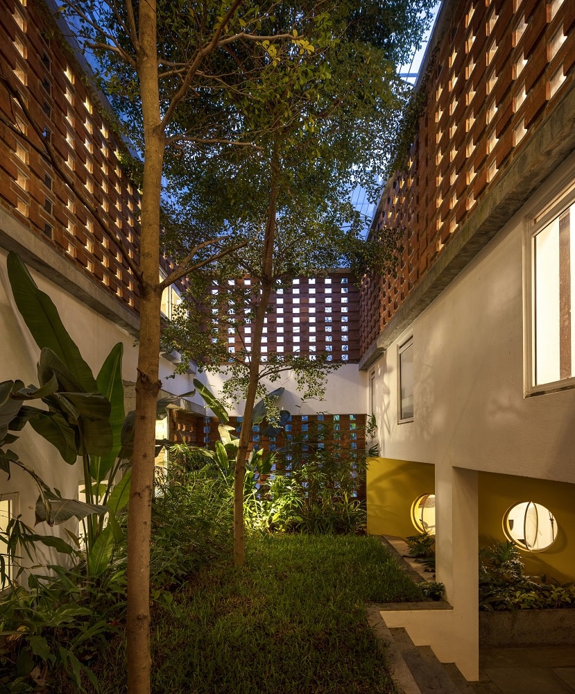 室内花园的夜景展示了景观和照明，与砖条投射出的温暖光线相匹配。