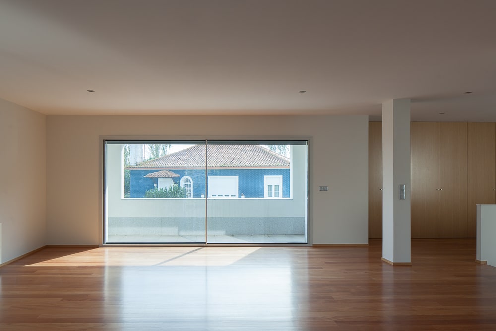 这是房子大房间的内部视图，宽敞的硬木地板搭配米黄色的墙壁，玻璃门和米黄色的天花板。