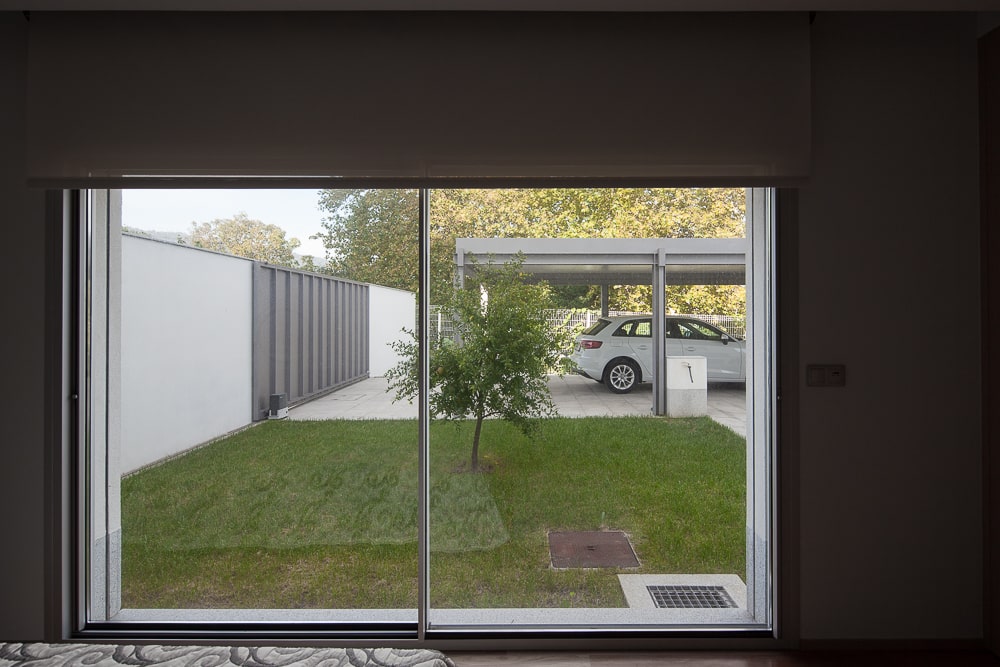 这是玻璃幕墙对草坪花园和车库汽车港口超越草坪的观点。