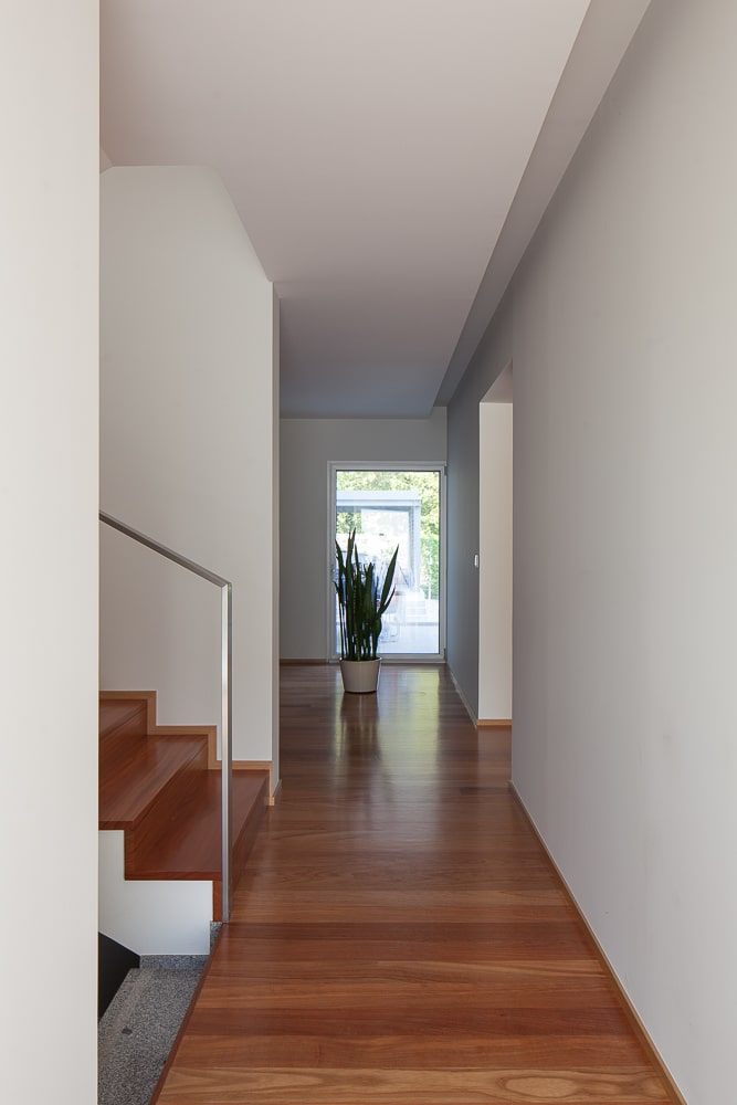 这是一个走廊和楼梯平台，硬木地板与楼梯的台阶相匹配，在另一端还有一盆植物。
