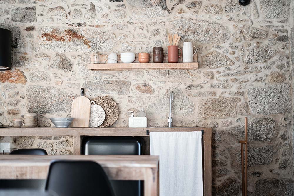 矩形餐桌的对面是远墙上的小厨房，有马赛克石材纹理的色调。