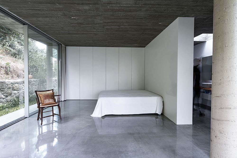 卧室闪亮的灰色地板与深色混凝土哑光天花板形成对比。