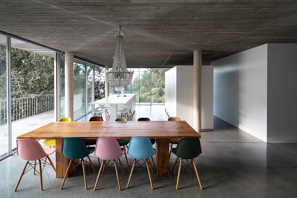 这是用餐区的另一个外观，有一个长方形的木制餐桌，周围环绕着彩色的椅子。