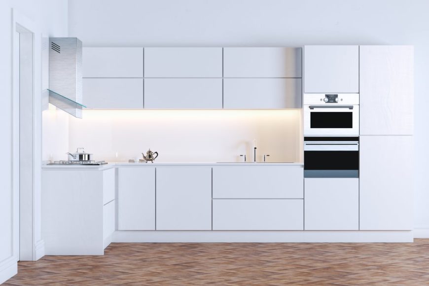 这是一个极简主义现代厨房的近距离观察，橱柜、柜台和后挡板与地板相辅相成，采用一致的白色调。