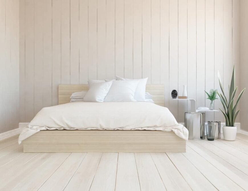 这是一个极简主义的卧室，它有一个木制的平台床，与周围的木制船搭墙和地板相匹配。