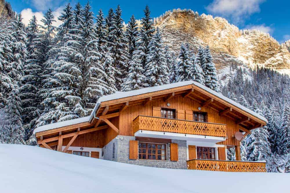 这是一个外表看山上的小木屋木搭叠外墙,带回家一个下雪的景色和背景的高大的松树。