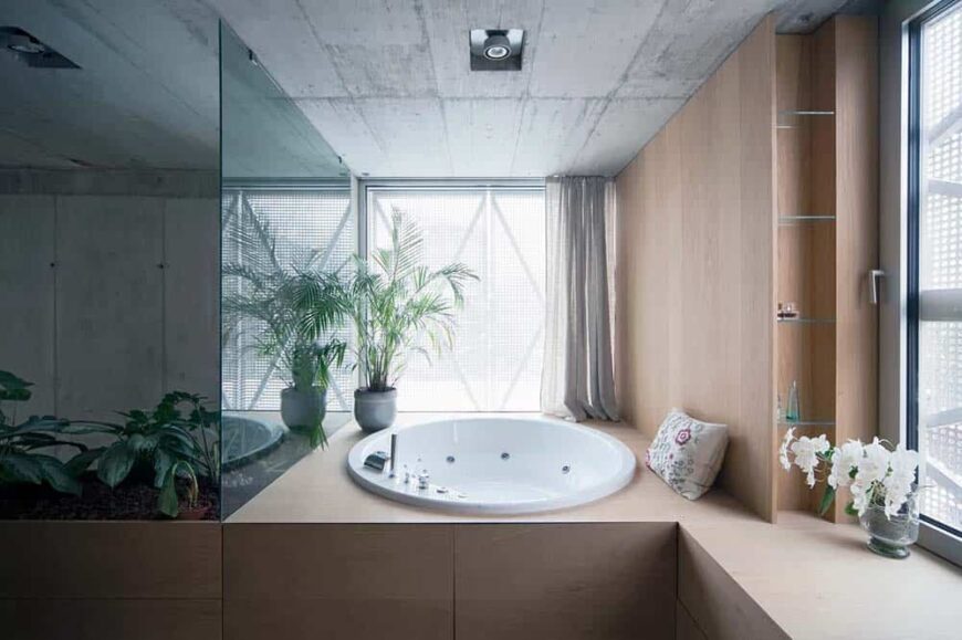 这是对主浴室的近距离观察，主浴室有一个大的木结构，窗户旁边有一个圆形浴缸，上面装饰着一盆植物。