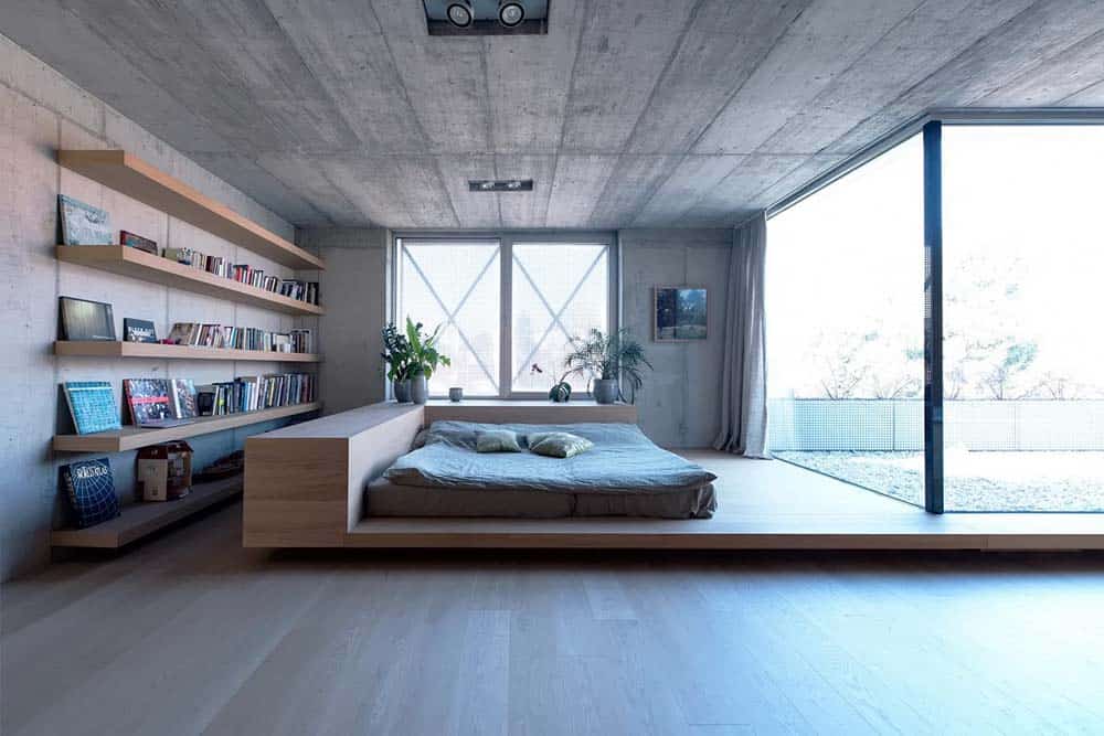 这是极简主义卧室的全貌，里面有一张木制台床，与侧面的木制浮动架子相匹配。