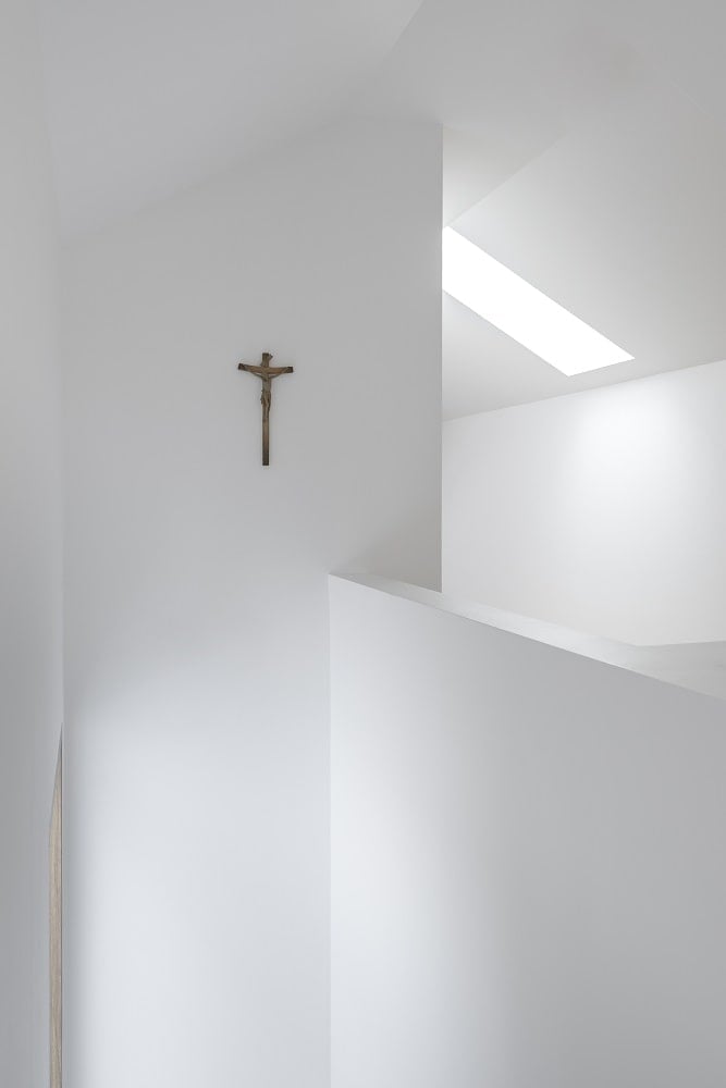 这是近距离观察修道院内部明亮的白墙之一，现代风格与墙上的十字架相辅相成。