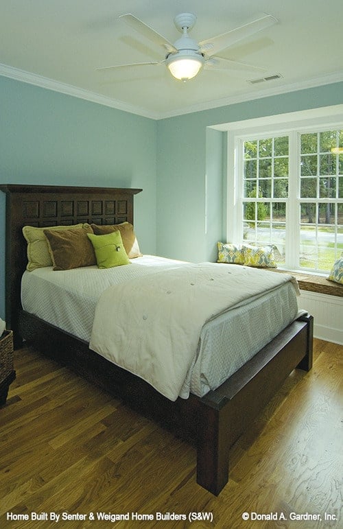 这间卧室有浅蓝色的墙壁，一张深色的木床，还有一个靠窗的角落。