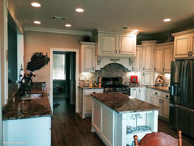 厨房提供白色橱柜，不锈钢器具，花岗岩台面，和一个中心岛。