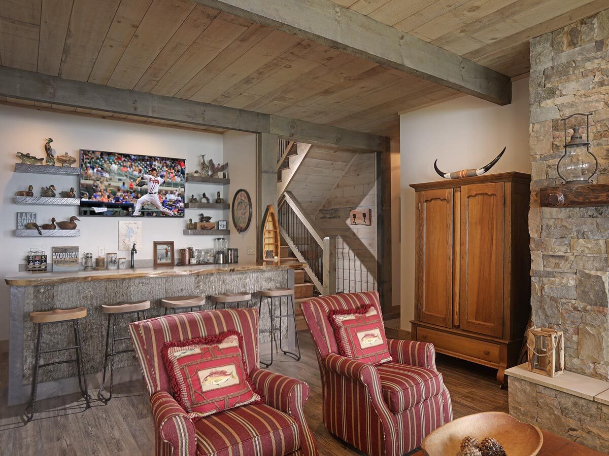 娱乐室有红色条纹扶手椅，木制橱柜，和一个大酒吧。