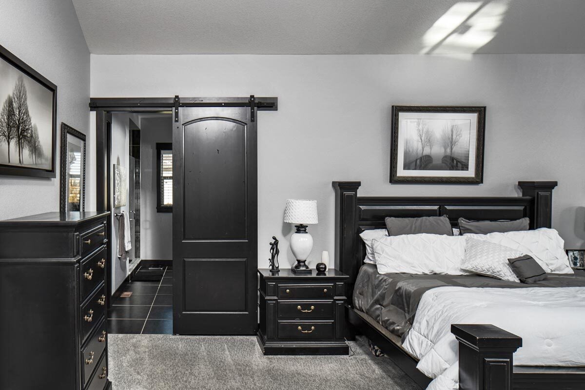 主卧室有大面积地毯和深色木家具，与谷仓滑动门的色调相匹配。