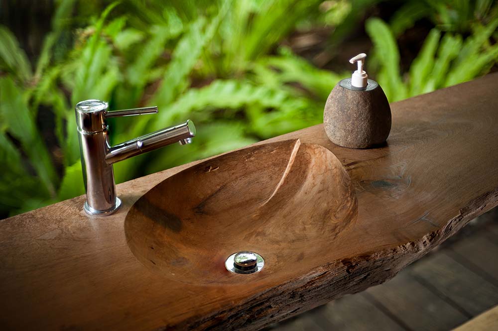 这是一个质朴的木制水槽，雕刻在一大块木材上，配有不锈钢固定装置。