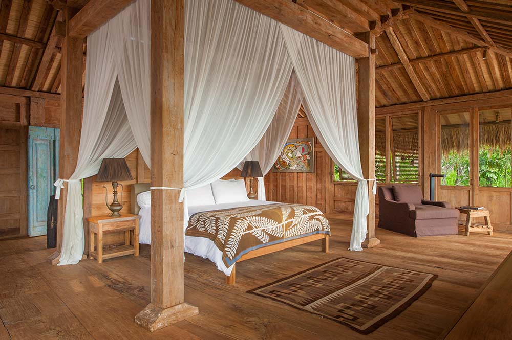 这是另一间卧室，有一张大木床，周围有四根木柱，床上挂着窗帘。