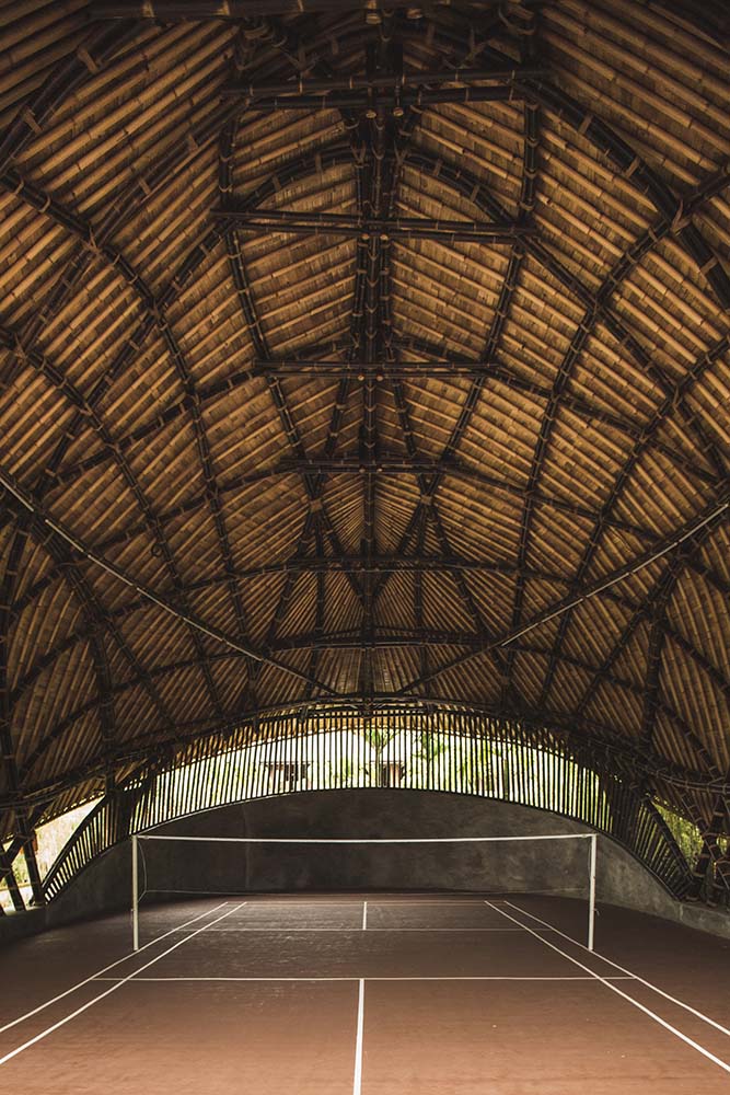 这是庭院的全貌，高高的天花板由竹子结构支撑，裸露的横梁和编织的热带树叶。