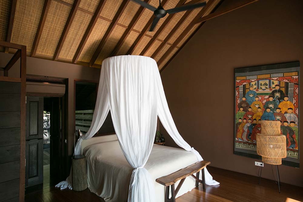 这是一个近距离观察的卧室，有一张白色的大床和白色的大窗帘来驱赶蚊子。