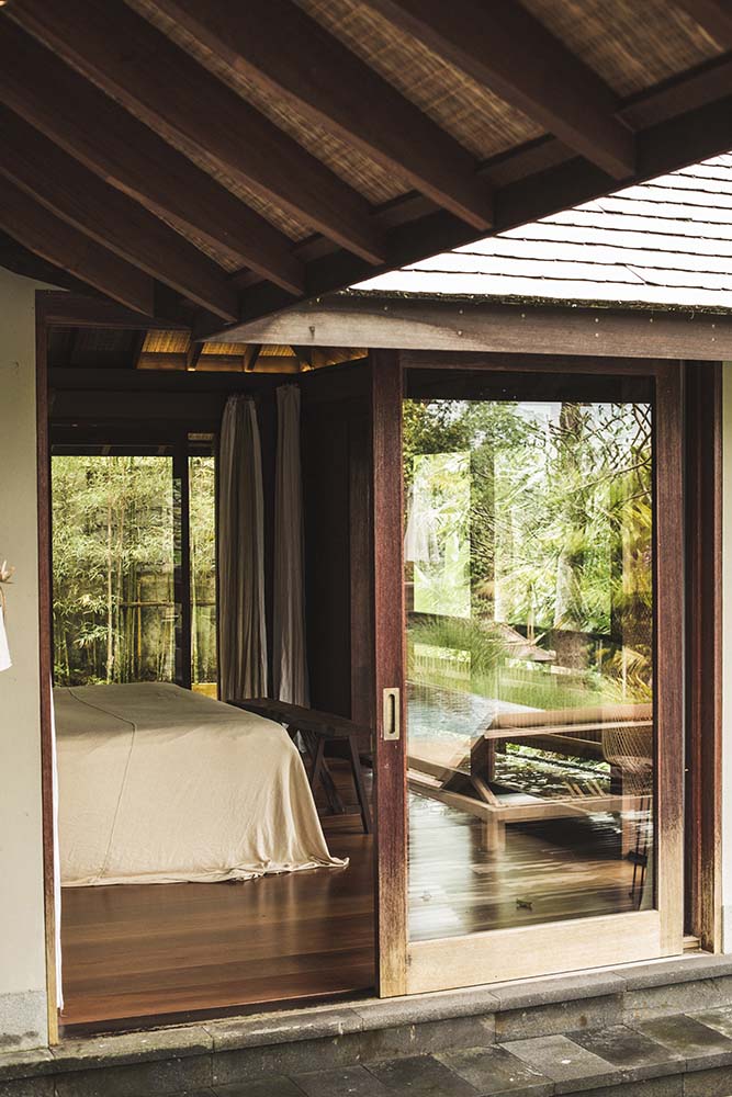 这是从玻璃推拉门外面看到的卧室，有木质地板和带横梁的木质天花板。