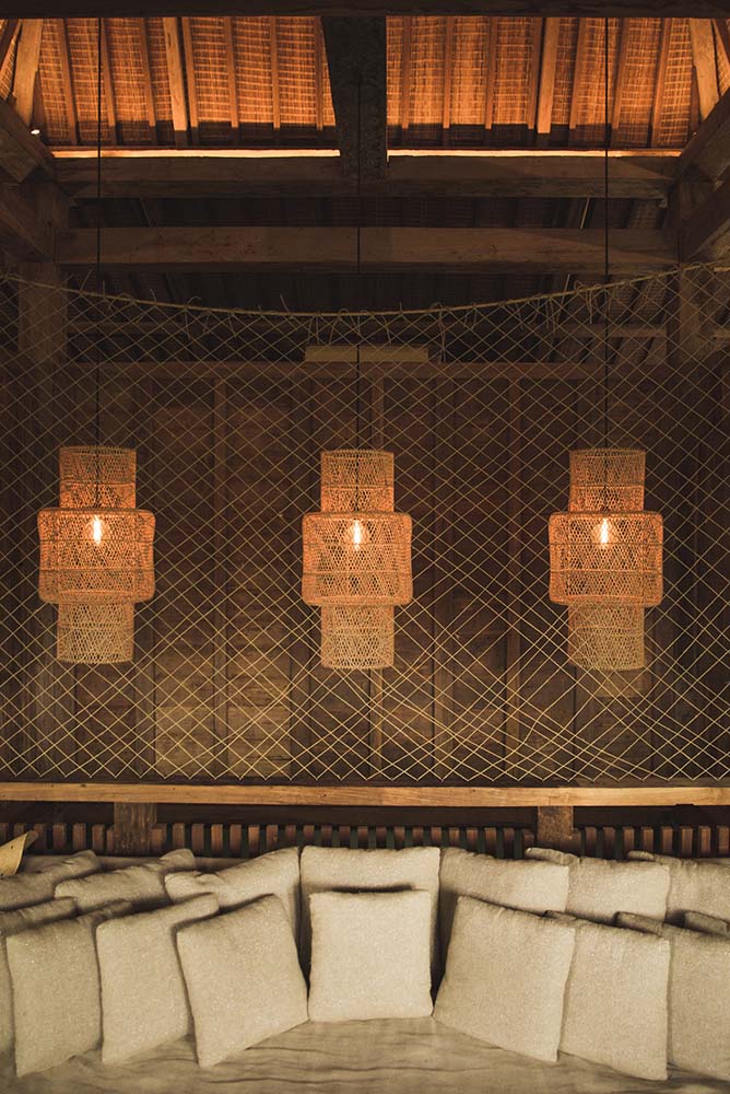 这是客厅的沙发，上面有三盏编织的柳条吊灯挂在木制天花板上。