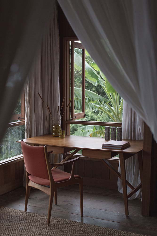 这是卧室的角落里有一个木制的桌子上明亮的玻璃窗与白色窗帘。