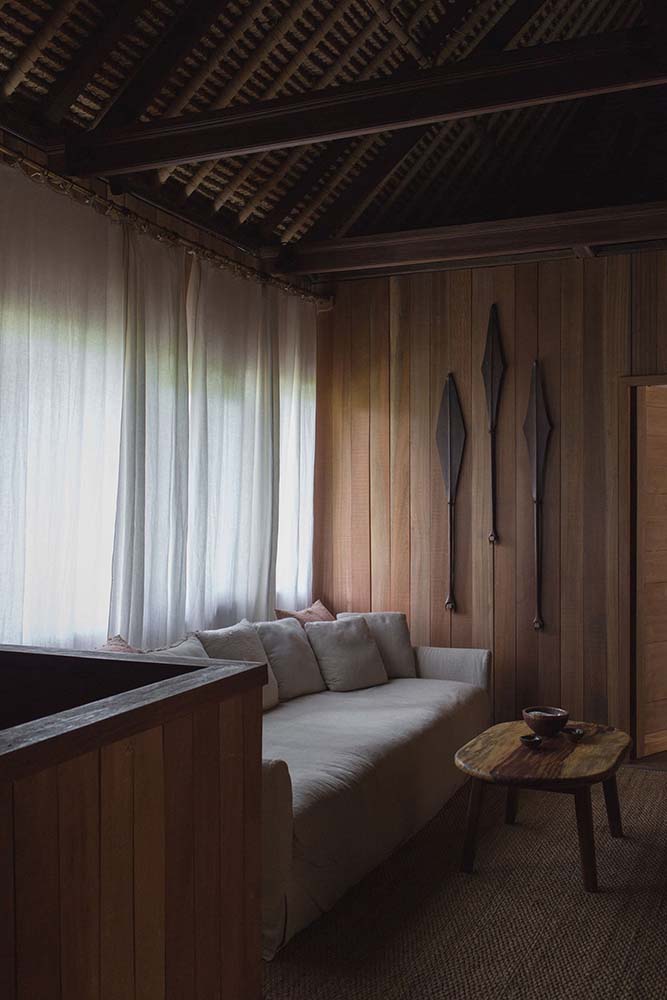 这个卧室有高大的木制墙壁的一边的沙发上,是一个内置的木质结构搭配了一个木制的咖啡桌顶部有一个木制的天花板。