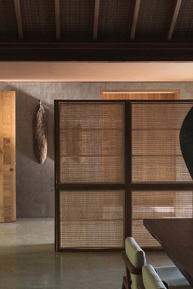 这个门厅有一个质朴的编织分隔板，将走廊与带有木制餐桌的用餐区分开。