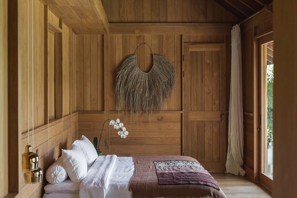 床在周围的木制元素和远处墙上装饰着乡村艺术品的墙壁上脱颖而出。