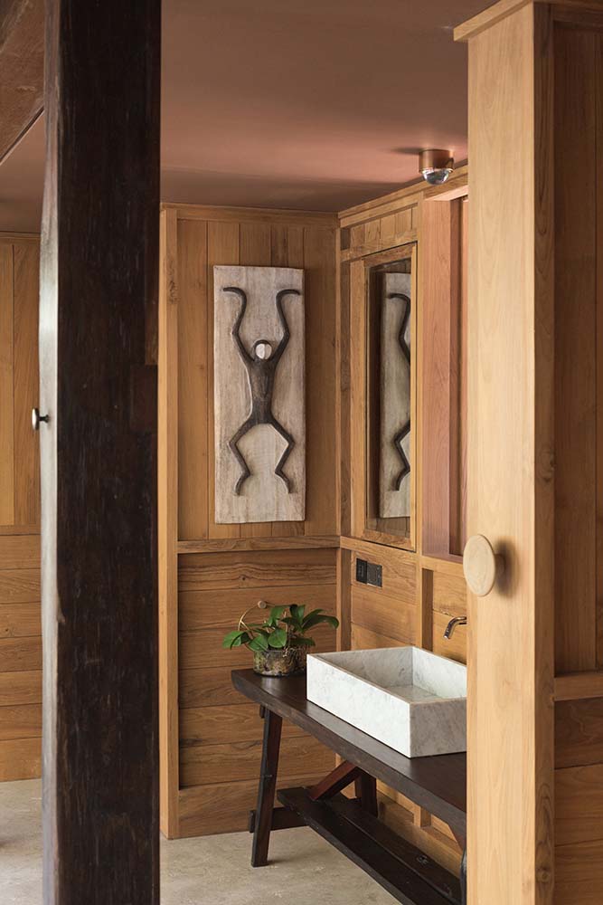 浴室里有一个简单质朴的梳妆台，搭配一个白色的矩形陶瓷水槽，水槽上装饰着一盆植物和壁挂式艺术品。