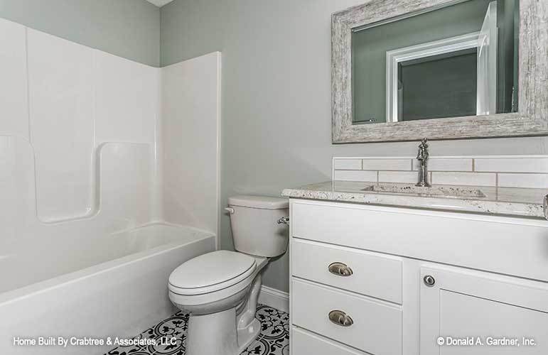 这个浴室提供浴缸和淋浴组合，一个厕所，一个白色的梳妆台和一面破旧的镜子。