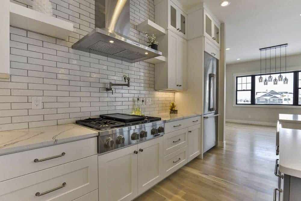厨房里有一个地铁瓷砖后挡板和一个内置灶台，搭配一个光滑的通风罩。