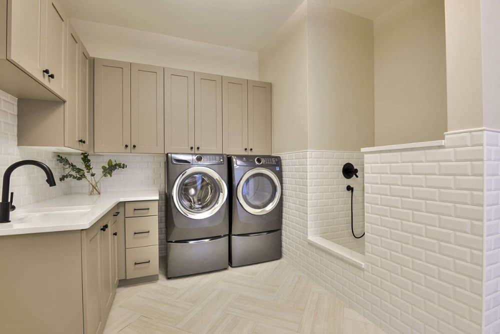 洗衣房，有灰褐色橱柜，前置电器，公用水槽和洗涤区。
