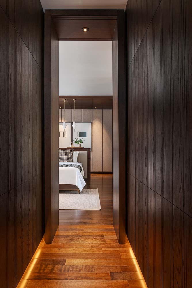 这是通往主卧室的狭窄走廊的近距离观察，主卧室的木墙与硬木地板相匹配。