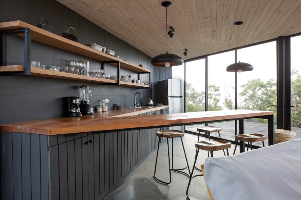 厨房里有一个v形的半岛，也兼作早餐吧台，配有配有锻铁腿的木凳，上面有黑色吊灯。