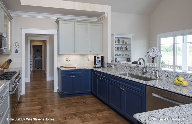 厨房有蓝色和白色的橱柜，花岗岩台面，不锈钢电器，和一个下置水槽。