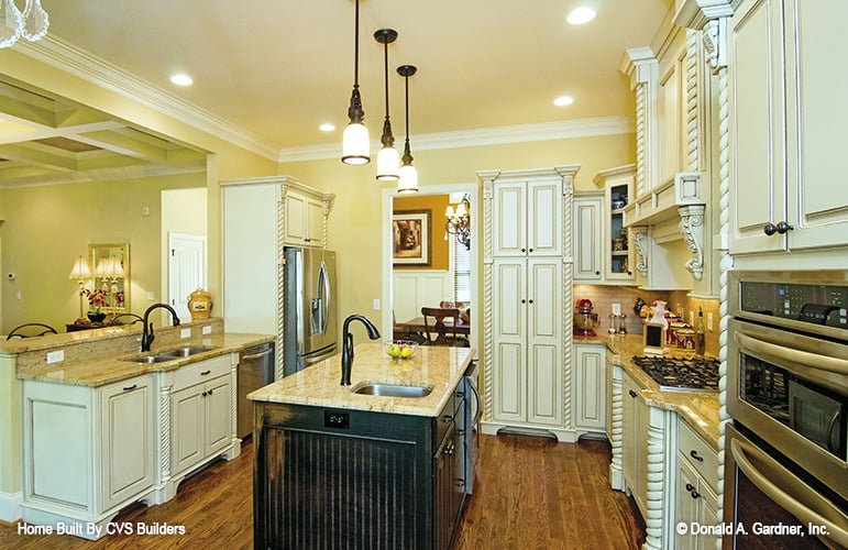 厨房有一个中央岛，凸起的饮食吧，白色的橱柜镶嵌着复杂的装饰。
