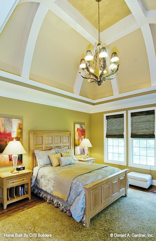 主卧室有浅色的木质家具，橄榄绿的墙壁，和一个高耸的凹形天花板。