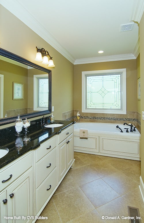 主浴室设有一个双洗手池梳妆台和一个深浴缸，放置在落地窗下。