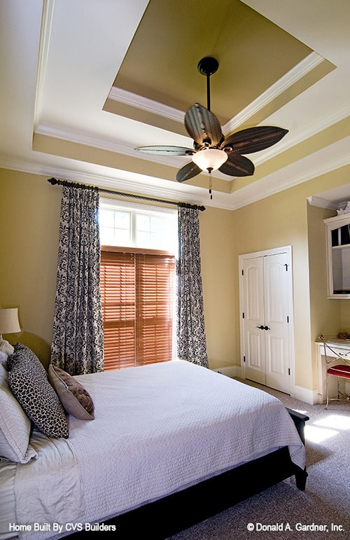卧室有地毯地板，步入式衣柜，和一个台阶天花板安装有装饰风扇。