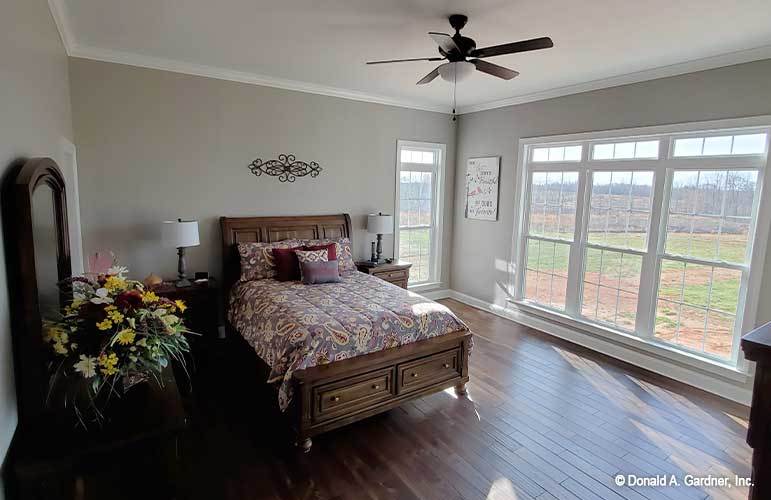 主卧室设有许多窗户和与硬木地板相匹配的木制家具。