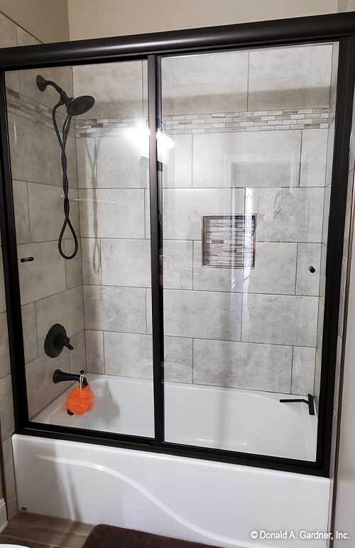 浴室带浴缸和淋浴组合，封闭在滑动玻璃门内。