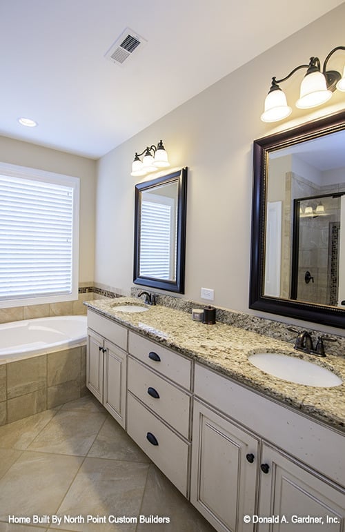 主浴室带有一个落地式浴缸和一个双洗手池梳妆台，配有镜框镜子。