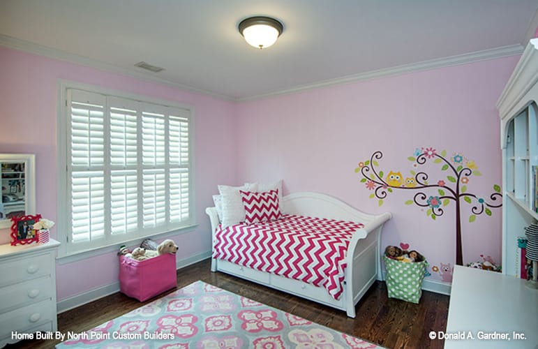 另一个孩子的卧室，有粉红色的墙壁，有图案的地毯，还有一张铺着红色人字形毯子的躺椅。