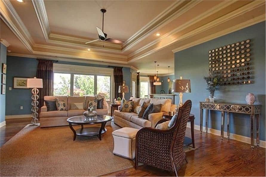 客厅提供米色的部分，柳条躺椅，和一个镀铬控制台桌面与镜面墙壁艺术。