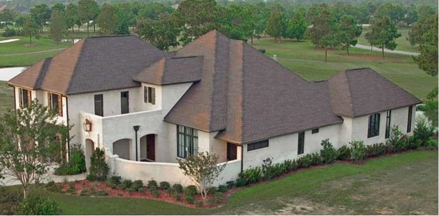 右前的外部视图显示了楔形的屋顶线，灰泥壁板，和绿色的景观围绕着房子。