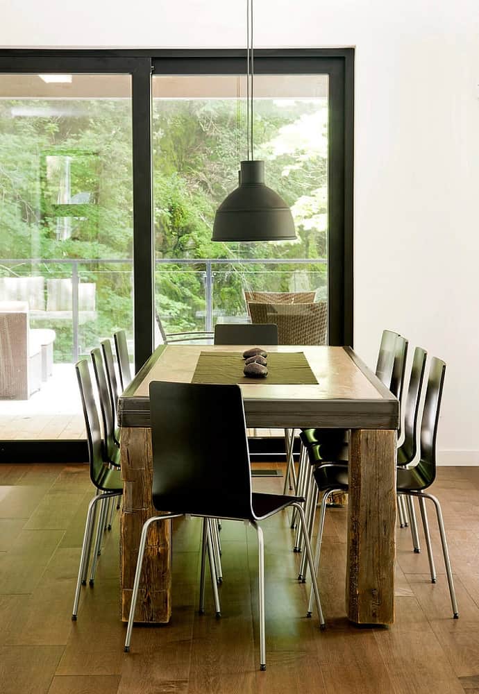 这是用餐区，一个长方形的餐桌与硬木地板相匹配。现代的黑色椅子和吊灯与之相得益彰。