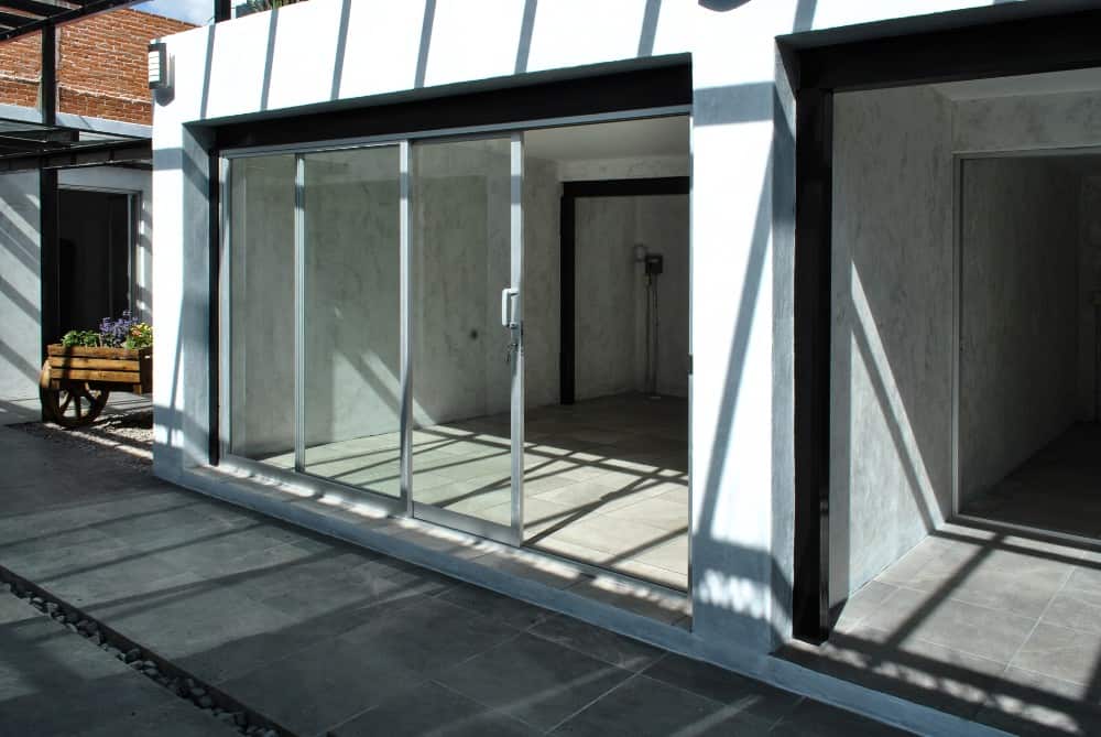 这是其中一扇滑动玻璃门，通往一间大的混凝土房间，里面铺着灰色地砖，采光充足。