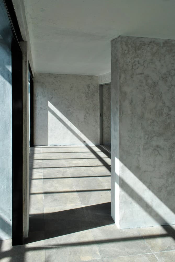 这是房子的内部视图，展示了宽敞明亮的房间，混凝土墙壁和灰色地砖。
